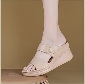 Vue latérale de mules beiges à talons compensés avec boucle en métal et surpiqûres.