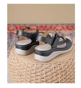 Detail view of black women's wedge sandals with white stitching on woven pouf