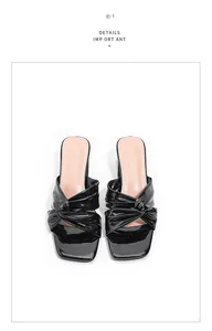 Close-up detail of black patent leather high heel slippers with twisted knot square toe
