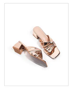 Detail view of elegant rose gold block heel sandals with knotted metallic straps.