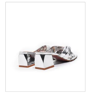 Detailed rear view of silver metallic block heel sandals featuring knotted strap design
