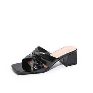 Elegant black patent leather block heel sandals with a twisted knot design and square toe.