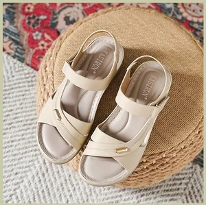 Detail view of beige wedge sandals with cross-strap design and gold accent buckle