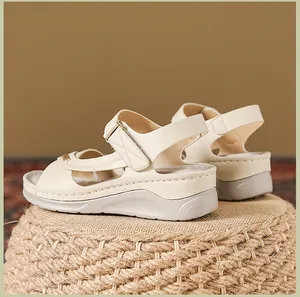 Detailed side view of beige women's wedge sandals with elegant white decorative stitching.
