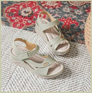 Detailed macro view of light green wedge sandals featuring stitching and gold metal accents