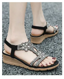 Detail view of black bohemian wedge sandals featuring shimmering rhinestone floral accents.