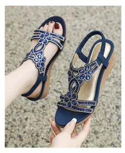 Close-up of bohemian blue wedge sandals featuring intricate rhinestone floral patterns