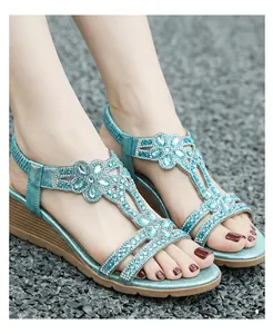 Close-up detail of teal bohemian wedge sandals with floral rhinestone embellishments