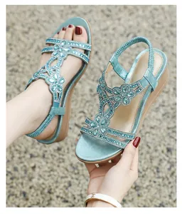 Close-up of bohemian turquoise wedge sandals featuring sparkling rhinestone flower details