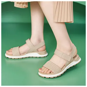 Detailed close-up of beige fly-woven sports sandals for women on a green background
