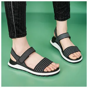 Close-up of black and white flyknit sporty sandals for women on a green background.