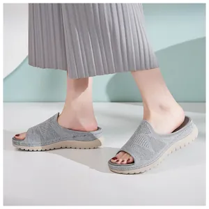 Vista lateral de sandalias de punto gris con suelas gruesas y cómodas en un modelo