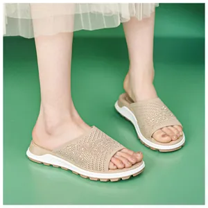 Detail view of breathable beige fly-knit slide sandals with sparkly rhinestone accents.