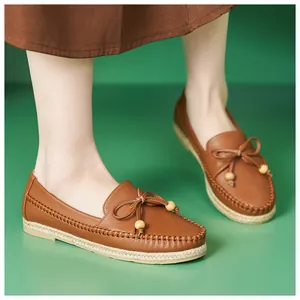 Detailed view of comfortable brown leather loafers with bow and bead details on green
