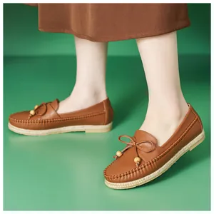 Women's brown leather loafers with bow and wood bead detail shown on feet