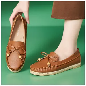 Close-up view of brown leather loafers with decorative bow and woven sole detail for women