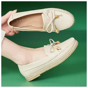 Detail of cream moccasins showing the bow tie, wooden beads, and textured material