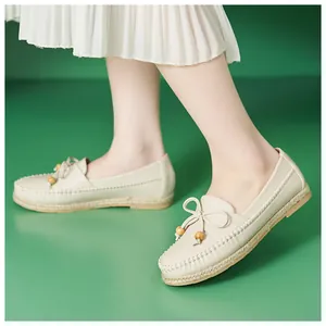 Close-up detail of beige casual loafers featuring a bow and decorative wooden beads.