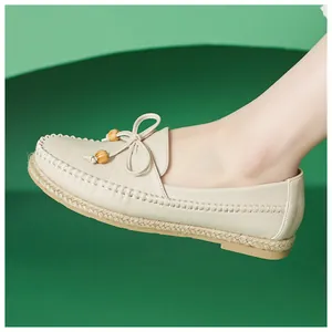Detail of cream-colored women's moccasins with leather texture and wooden bead bow