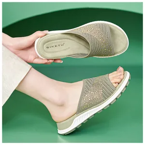 Close-up of green knit slide sandals with sparkling rhinestone embellishments and flat sole.