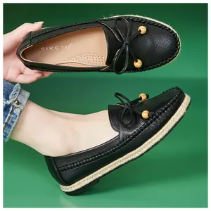 Close-up view of comfortable black leather loafers with bow and jute-wrapped sole details