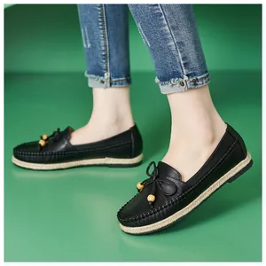 Close-up detail of stylish black leather loafers with bow tie and wooden bead accents