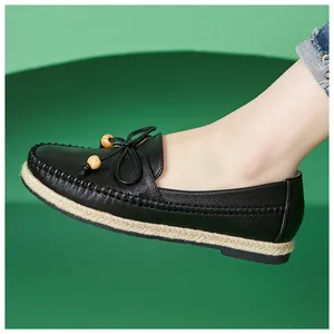 Close-up of black leather loafers featuring bow and bead details on green background