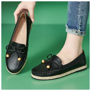 Close-up of black women's loafers featuring a bow tie with wooden beads and a soft sole