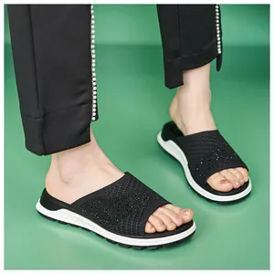 Close-up of black fly-knit slippers with rhinestones on a model's feet