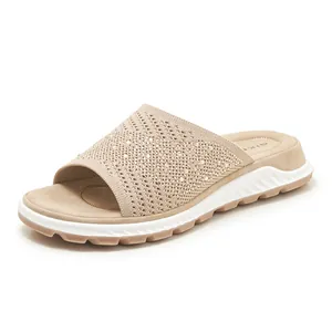 Close-up of fly-knit upper with shimmering rhinestone details on beige slide sandals.
