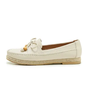 Side view detail showing the pebbled leather texture and wooden bead bow on beige loafers