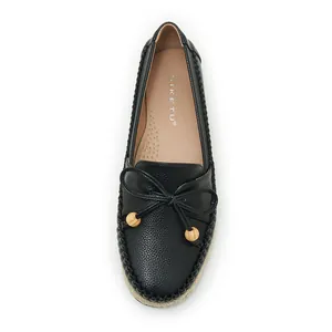 Top view of black loafers featuring a decorative bow with wooden beads and textured upper