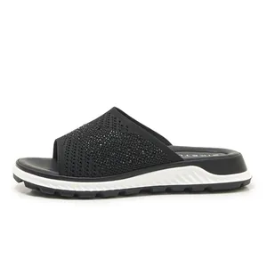 Side view of women's black fly-knit slide sandals with sparkling rhinestone details.