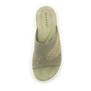 Close-up of green fly-knit sandal featuring elegant gold rhinestone patterns