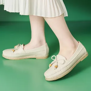 Comfortable beige women's loafers with bow and bead detail on a bright green background
