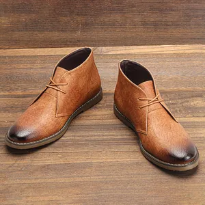 Botas desert vintage para hombre en color marrón con punta bruñida sobre madera