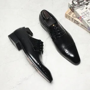 Detaillierte Ansicht schwarzer Herrenschuhe mit Krokostruktur auf Marmoroberfläche