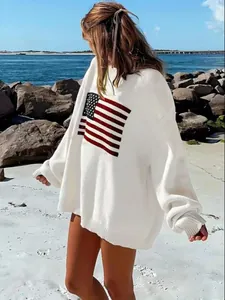 Detailed view of white oversized sweater with American flag design on beach