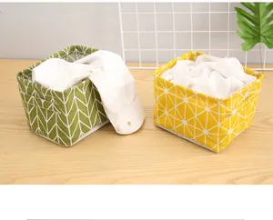 Two stylish patterned cotton linen storage baskets in green and yellow on a wooden surface