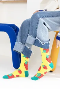 Vue détaillée de chaussettes mi-mollet jaunes à motifs de fraises rouges et verts.