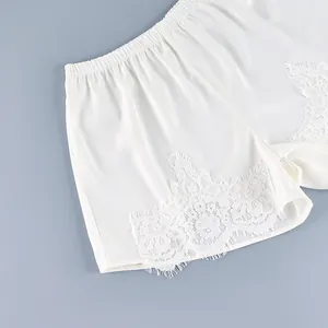 Primer plano de shorts de satén blanco con encaje delicado y cintura elástica.