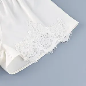 Primer plano de unos elegantes pantalones cortos de satén blanco con encaje detallado.