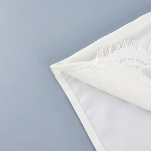 Detalle de pantalones cortos de satén blanco con encaje de pestañas y costura