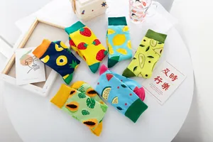 Détail de chaussettes en coton mi-hautes colorées avec motifs de fruits vifs sur table