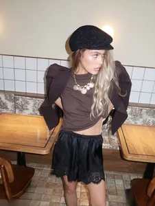 Detalle de pantalones cortos de satén negro con encaje en un elegante entorno de cafetería