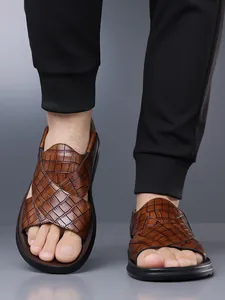 Nahaufnahme von braunen Herren-Sandalen mit Krokodilmuster und dicken schwarzen Sohlen.