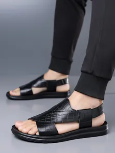 Detailansicht von schwarzen Herren-Sandalen aus Leder mit Krokodilprägung und dicken Sohlen.