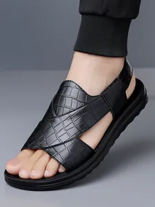 Nahaufnahme der schwarzen Herren-Sandalen mit Krokodil-Textur und dicker Gummisohle