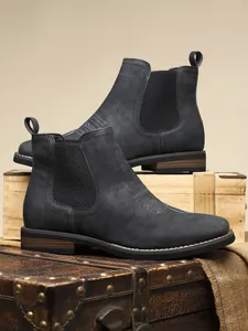 Detail showing dark grey suede men's Chelsea boots on vintage wooden crates