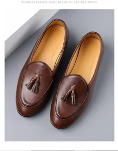 Draufsicht auf braune Leder-Loafer mit Quasten auf minimalistischem grauem Grund
